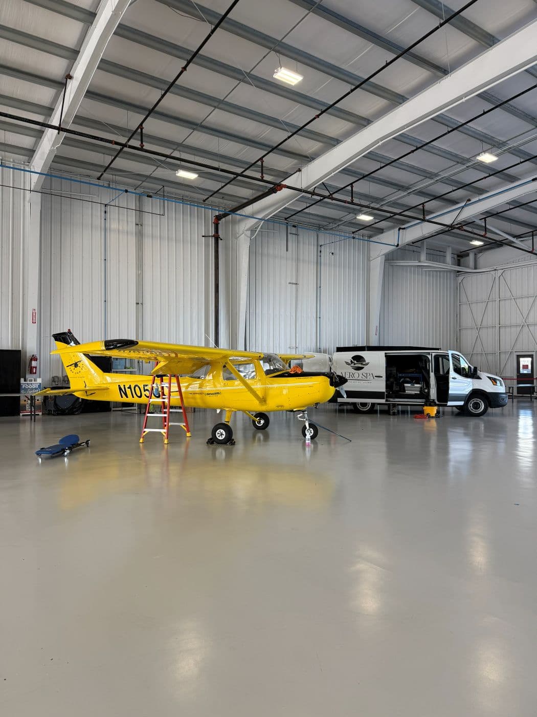 Yellowbird, a yellow Cessna 152, in the hangar with the Aero Spa van behind it