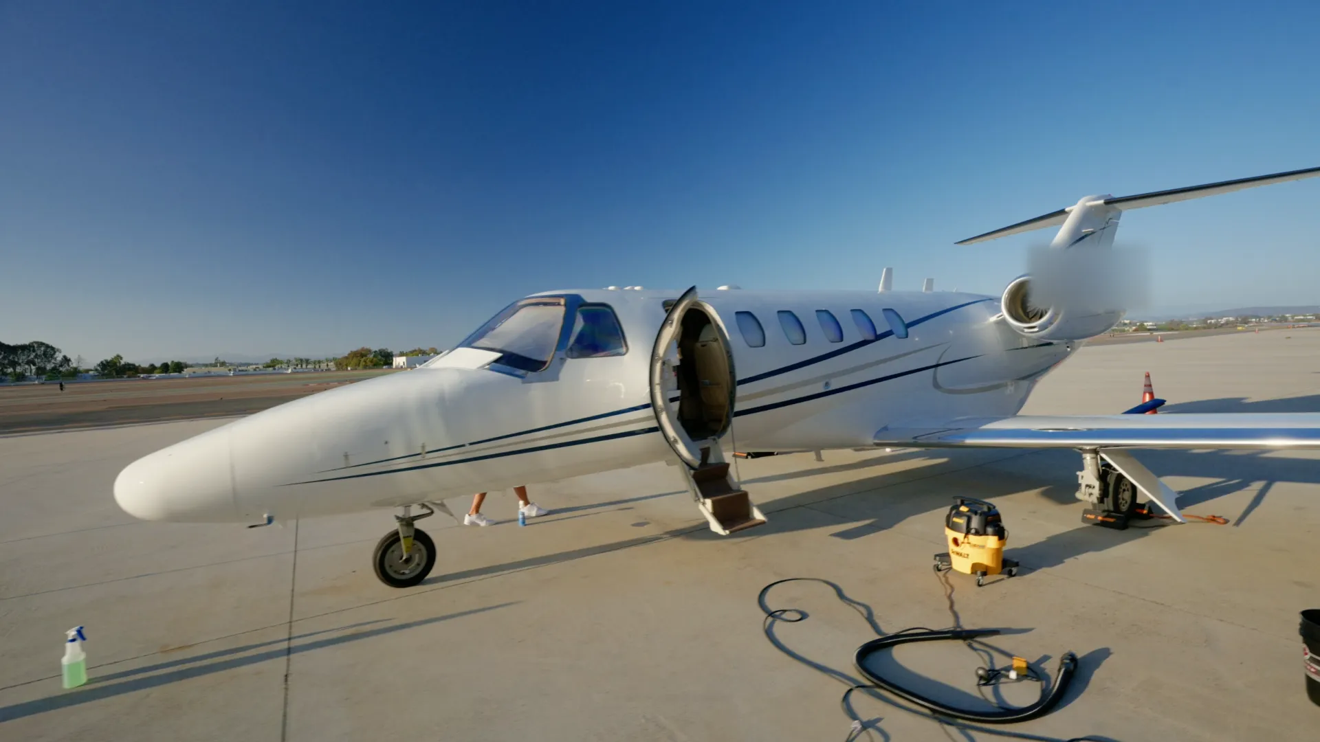 A Citation jet on the ramp at McClellan-Palomar with its cabin door open and detailing equipment beside it